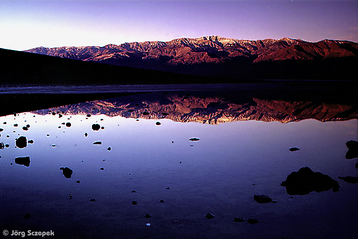 Blick vom Badwater Point im Death Valley auf die im Licht des Sonnenaufgangs badenden Panamint Mountains