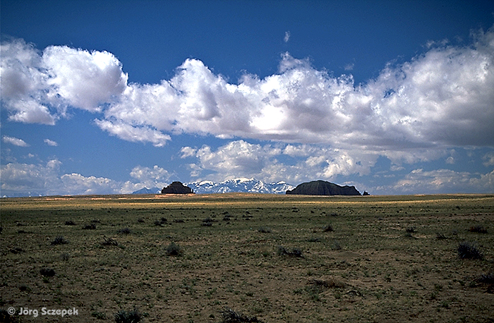 Blick über die weite Ebene an der Rt-24 in der Nähe des Goblin Valley SP auf die Henry Mountains am Horizont